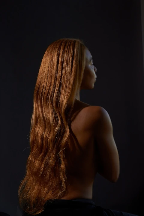 Side-profile portrait of Daisi Jo with long hair against a dark background